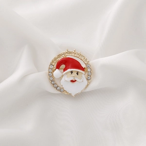Christmas Santa Claus brooch with rhinestones and gold frame on white silk background