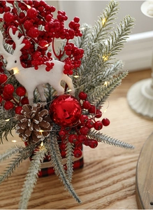 Close-up of Christmas table decor with red berries, pine cones and a white reindeer