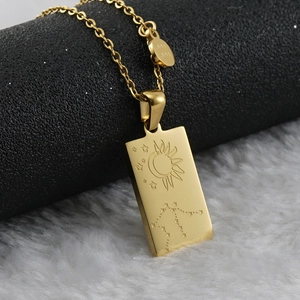 Macro view of 18K gold zodiac pendant featuring sun and moon engravings on square steel