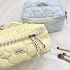 Detail of heart quilted cosmetic bags with woven ribbon zippers and soft puffy fabric