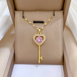 Detailed close-up of a luxury gold heart key pendant with pink crystal and tiny diamonds