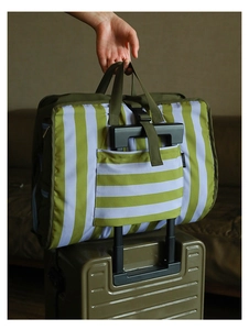 Olive green travel organizer bag secured to suitcase handle showing trolley sleeve detail