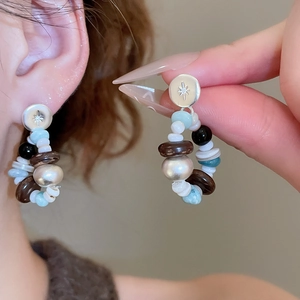 Detail of bohemian beaded earrings with silver star studs and multi-color stone beads