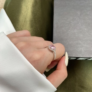 Detail of pink oval gemstone ring with side pave diamonds on green silk background