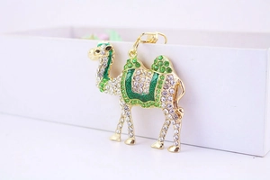 Detailed view of camel keychain with gold plating, green and white rhinestones