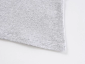Detailed macro view of the double-stitched hem on a grey knit cotton T-shirt