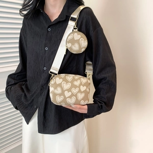 Detail of khaki crossbody bag with heart pattern and a round coin purse on wide strap