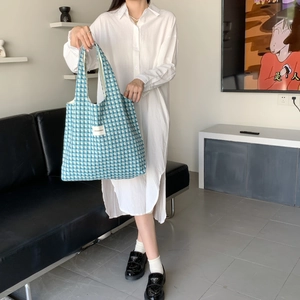 Blue and white houndstooth woven tote bag detail with brand label and top handle style