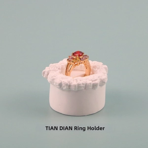 Close-up of golden flower ring with red and pink gemstones on a white resin jewelry stand