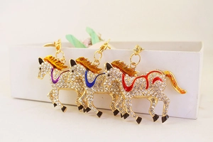 Detailed view of three golden running horse keychains with purple, blue and red rhinestones