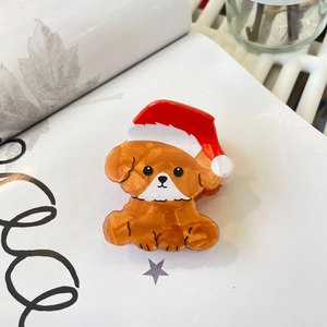 Detail of cute acrylic puppy hair claw clip with festive red and white Christmas hat