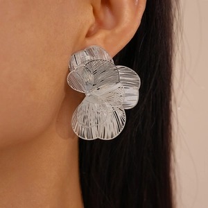 Detail of silver layered hollow petal earrings with textured metal on female model