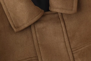 Detailed macro view of the brown suede bomber jacket collar with precision stitching