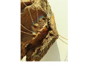 Artistic close-up of 18K gold cubic zirconia pendant necklaces on a wooden block