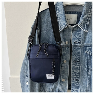 Detail view of navy blue nylon crossbody phone bag with Hello Weekend patch on denim jacket