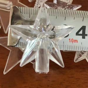 Close-up of a 4cm transparent star-shaped plastic Christmas ornament with a measuring tape