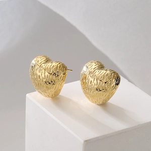 Retro heart-shaped earrings with textured 18K gold finish on a minimalist white stand