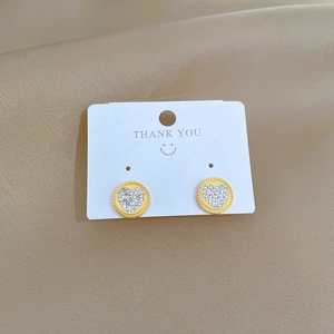 Minimalist gold circle heart stud earrings with white cubic zirconia on silk fabric
