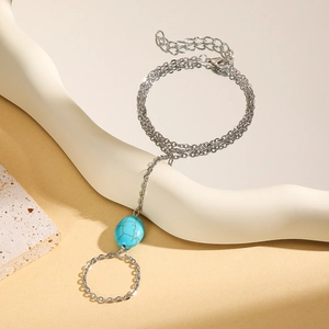 Detail of silver-tone slave bracelet featuring turquoise stone on white display
