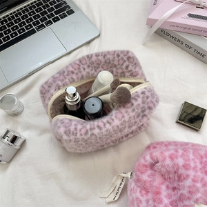 Interior view of a plush pink leopard print makeup bag holding cosmetics and brushes
