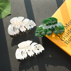 Three rhinestone leaf-shaped claw clips in gold-line transparent, white and dark green