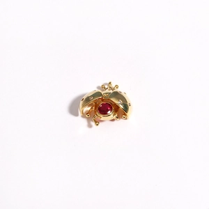 Close-up of golden ladybug pendant with red gemstone and sparkling rhinestone details