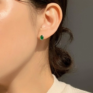 Detail of elegant sterling silver earrings with green oval agate stone worn by a model