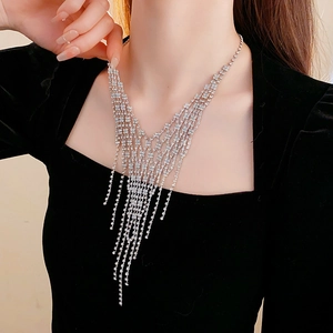 Macro shot of silver tassel necklace with diamond accents on model for layered styling