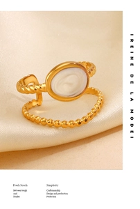 Close-up of dual-layer gold-plated ring with twisted bead texture on cream satin