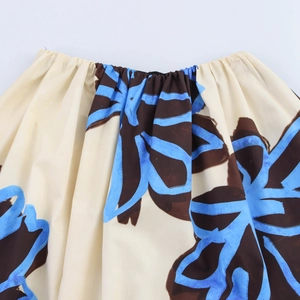 Detail shot of elastic off-shoulder neckline with blue floral print on beige fabric