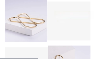 Polished gold infinity twist earrings with high-gloss finish on a white stone base