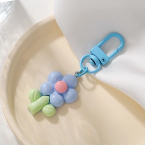 Close-up of a blue tulip flower keychain with a pink center on a beige ceramic plate