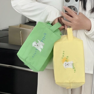 Close-up of yellow canvas dog makeup bag with handle held by hand in a real-life setting