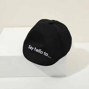 Close-up of black cotton baby beret featuring white Say hello to embroidery detail