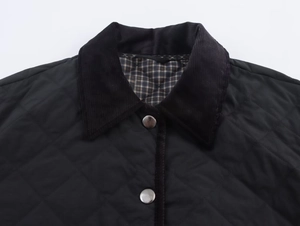 Detail of black quilted jacket with corduroy collar, silver buttons and plaid lining