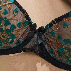 Détail de broderie florale verte et nœud sur un ensemble de lingerie en dentelle