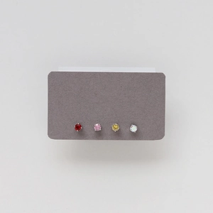 Detail of four-color round claw-set stud earrings in silver-toned titanium steel