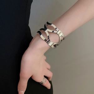 Close-up of polished silver cutout cuff bracelet and criss-cross ring on model