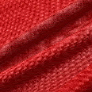 Macro shot of breathable red polo shirt fabric texture with detailed weave pattern