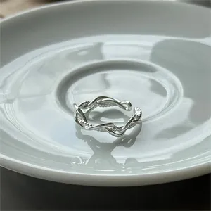 Macro shot of silver woven adjustable open ring on a white minimalist ceramic plate