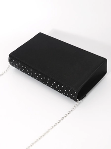 Detail of black satin evening clutch featuring rhinestone trim and silver chain strap
