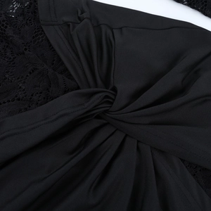 Close-up of black lace patchwork and knot detail on a sheer long-sleeved dress