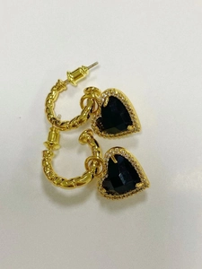 Dettaglio ravvicinato di orecchini a cuore placcati oro con pietra nera e cristalli