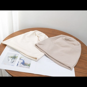 Detailed close-up of cream and light brown knit beanies on a rustic wooden table