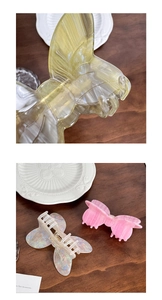 Close-up of colorful acetate bow hair clips in yellow and pink on a wooden desk