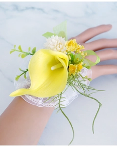 Detailed view of a yellow calla lily wrist corsage with lace band and green ribbons