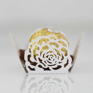 Detail of white laser-cut rose hollow cupcake liners with gold chocolate tray