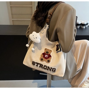Dettaglio della borsa tote in tela retrò con toppa a forma di orso e manici in pelle