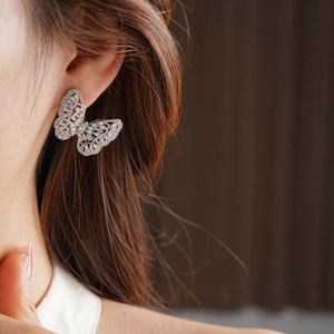 Detail shot of micro-pave cubic zirconia butterfly earrings worn on a model ear