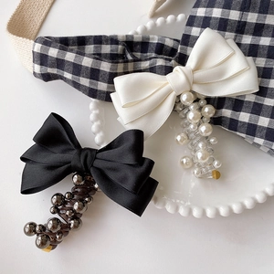 Bow pearl spiral hair ties in black and cream white silk on a decorative white plate